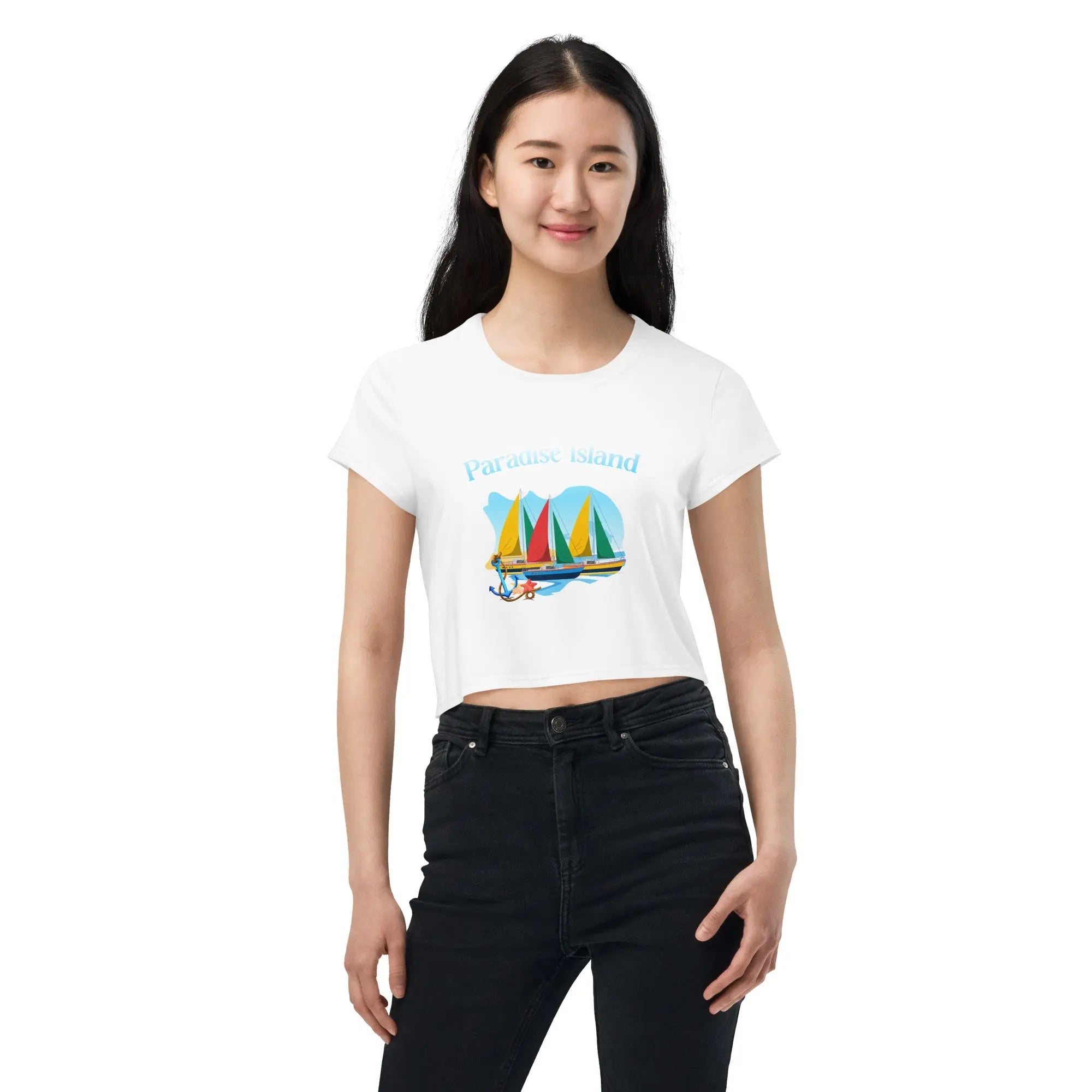 Woman wearing Paradise Island All-Over Print Crop Tee with colorful sailboat design and black jeans