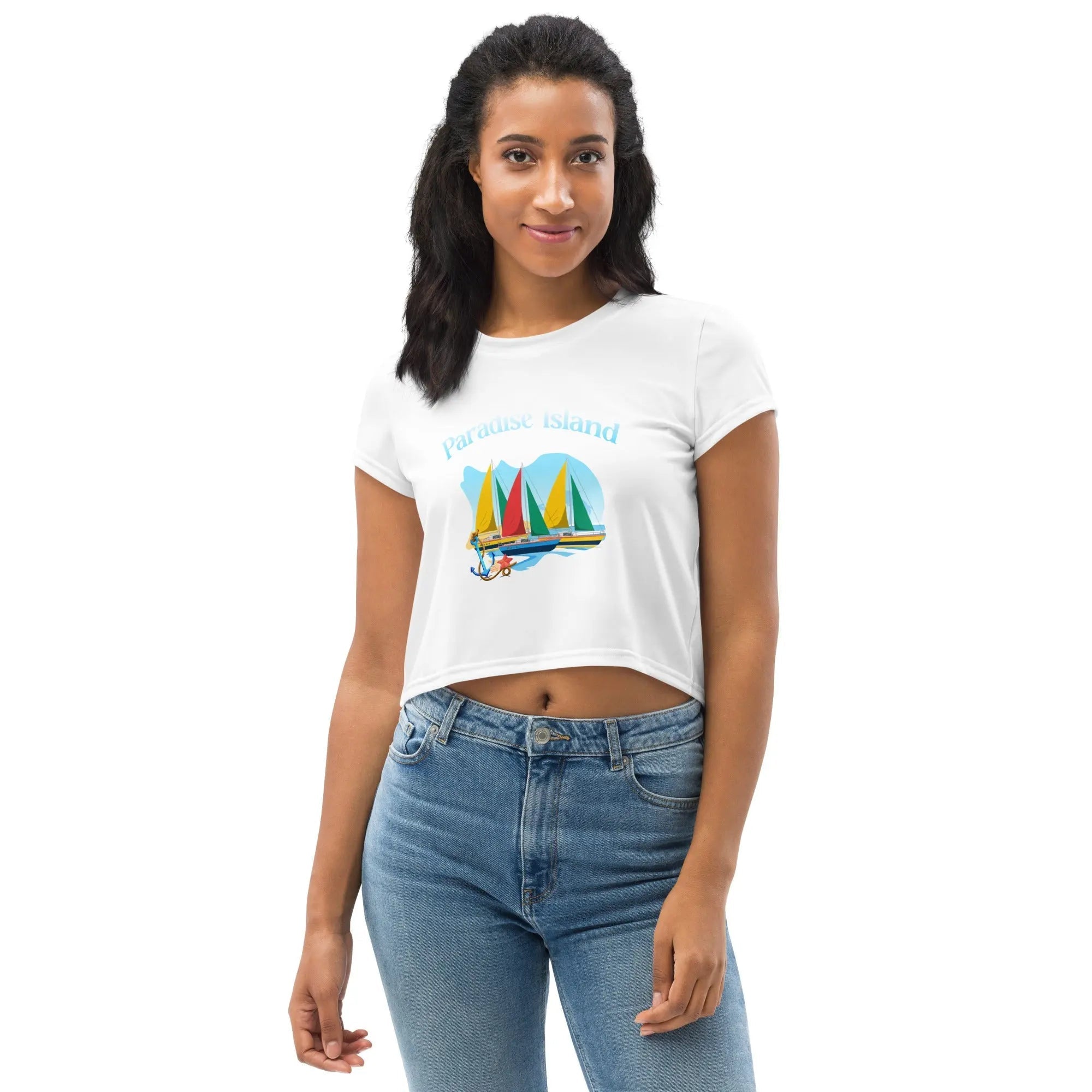 Woman wearing white Paradise Island All-Over Print Crop Tee with colorful sailboat graphic and blue jeans