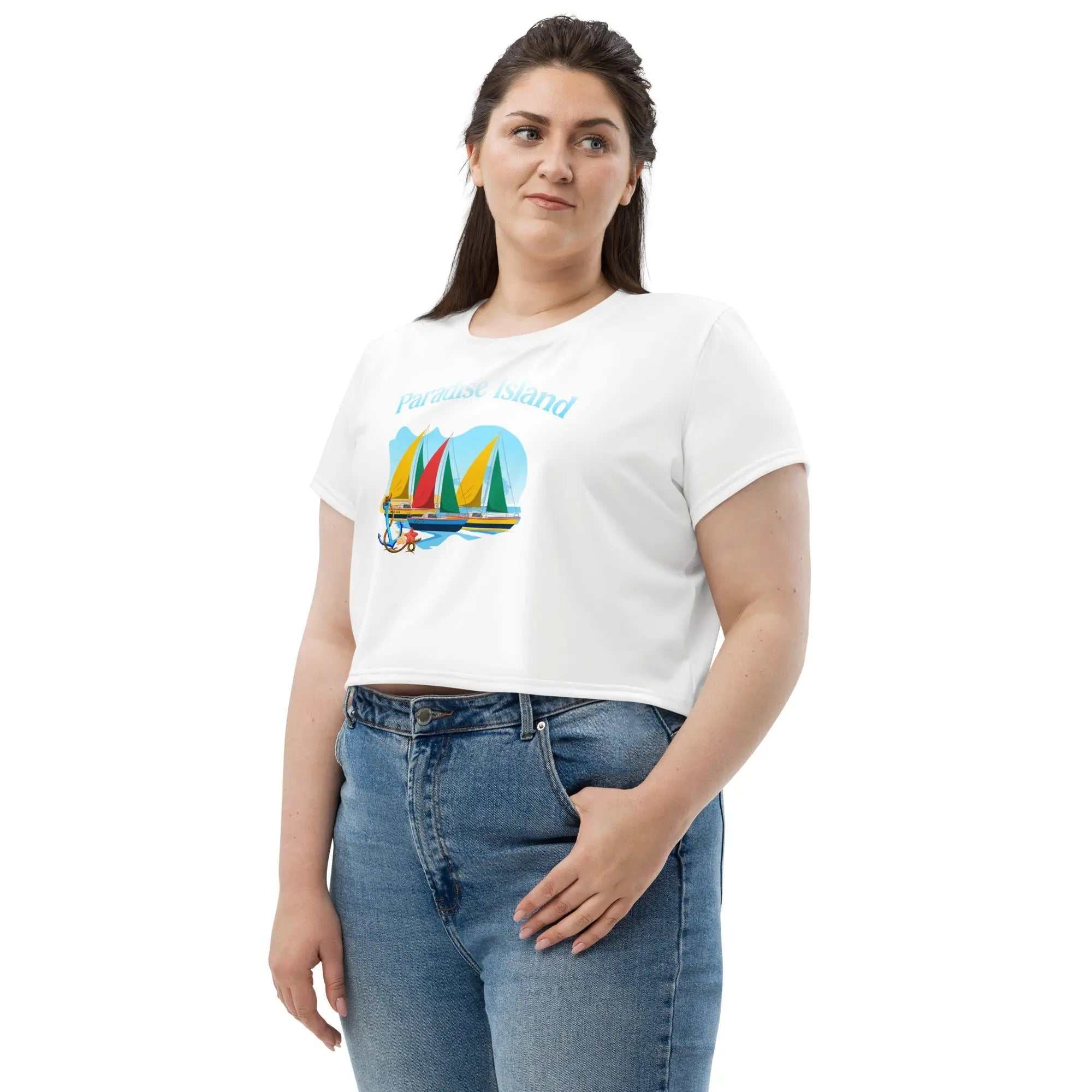 Woman wearing Paradise Island all-over print white crop tee with colorful sailboat graphic and blue jeans