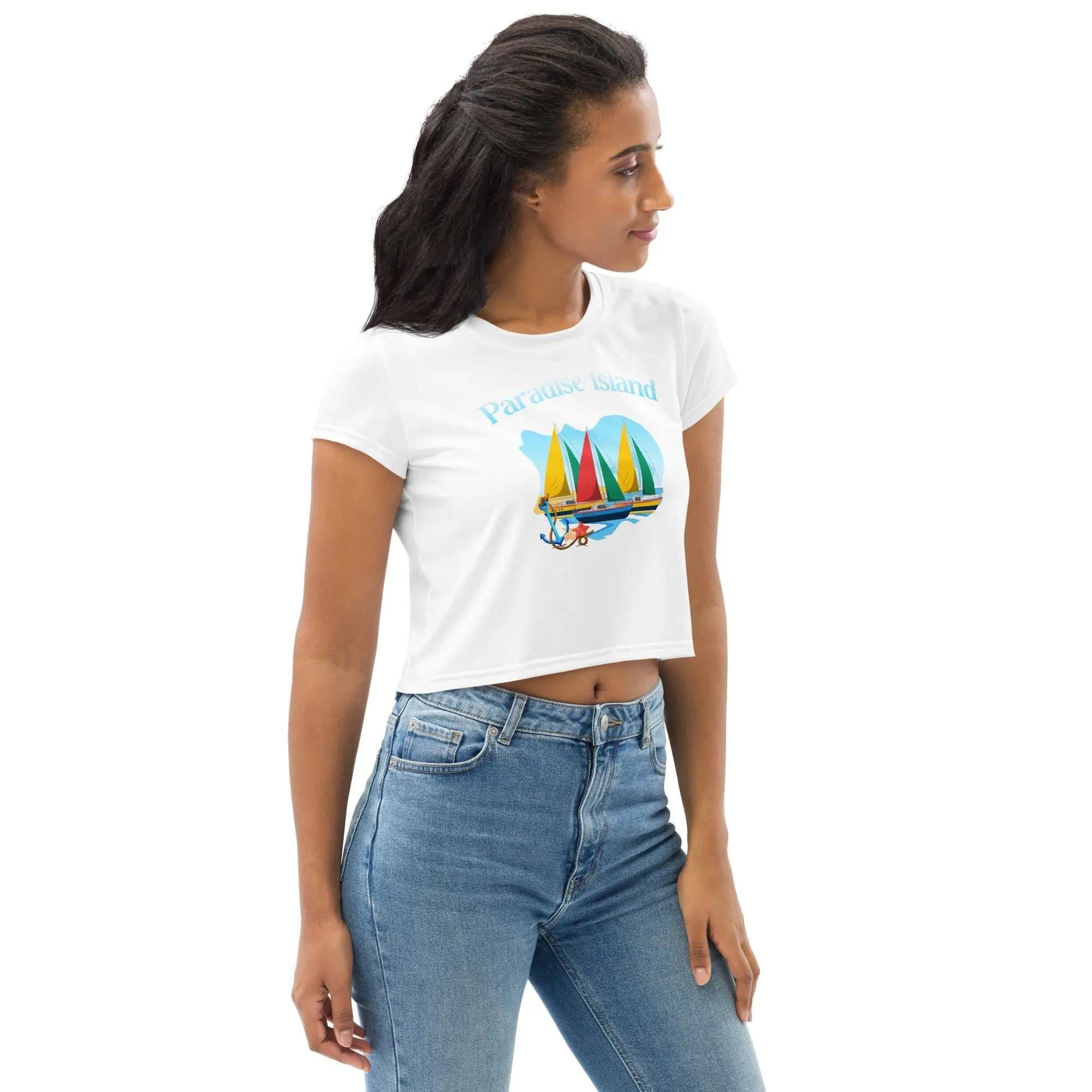 woman wearing Paradise Island All-Over Print crop tee with colorful sailboats design and fitted blue jeans
