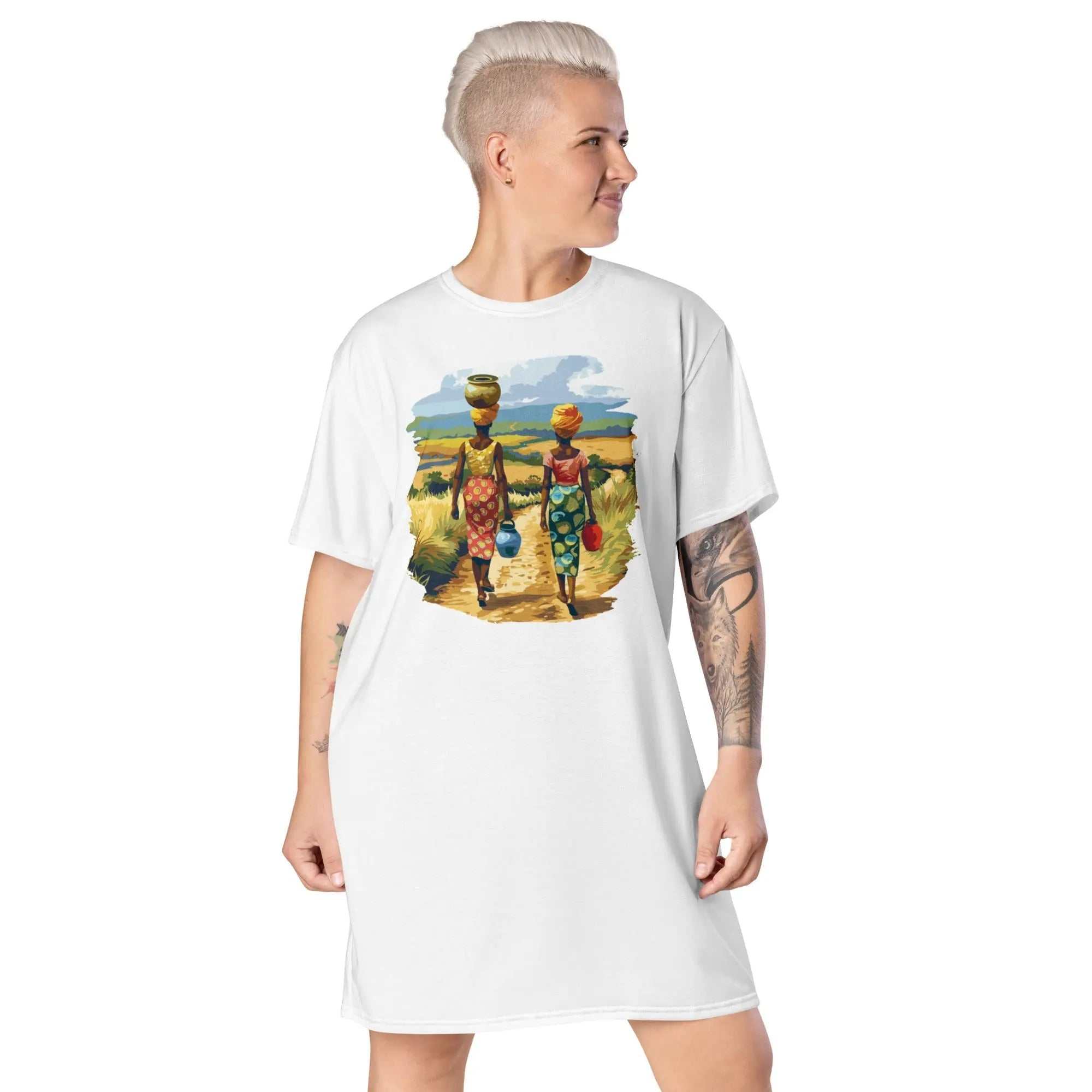 Woman wearing white African Journey Tee Dress featuring colorful illustration of two African women carrying baskets on heads walking on a rural path