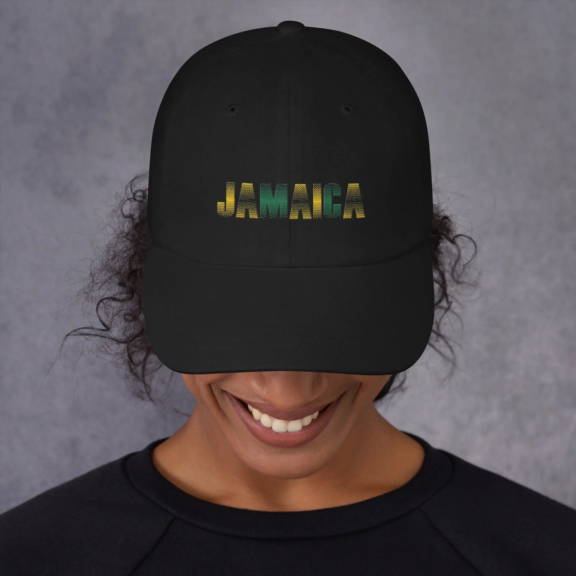 Black Jamaica Unisex Dad Hat with colorful embroidered text and curved visor worn by smiling person
