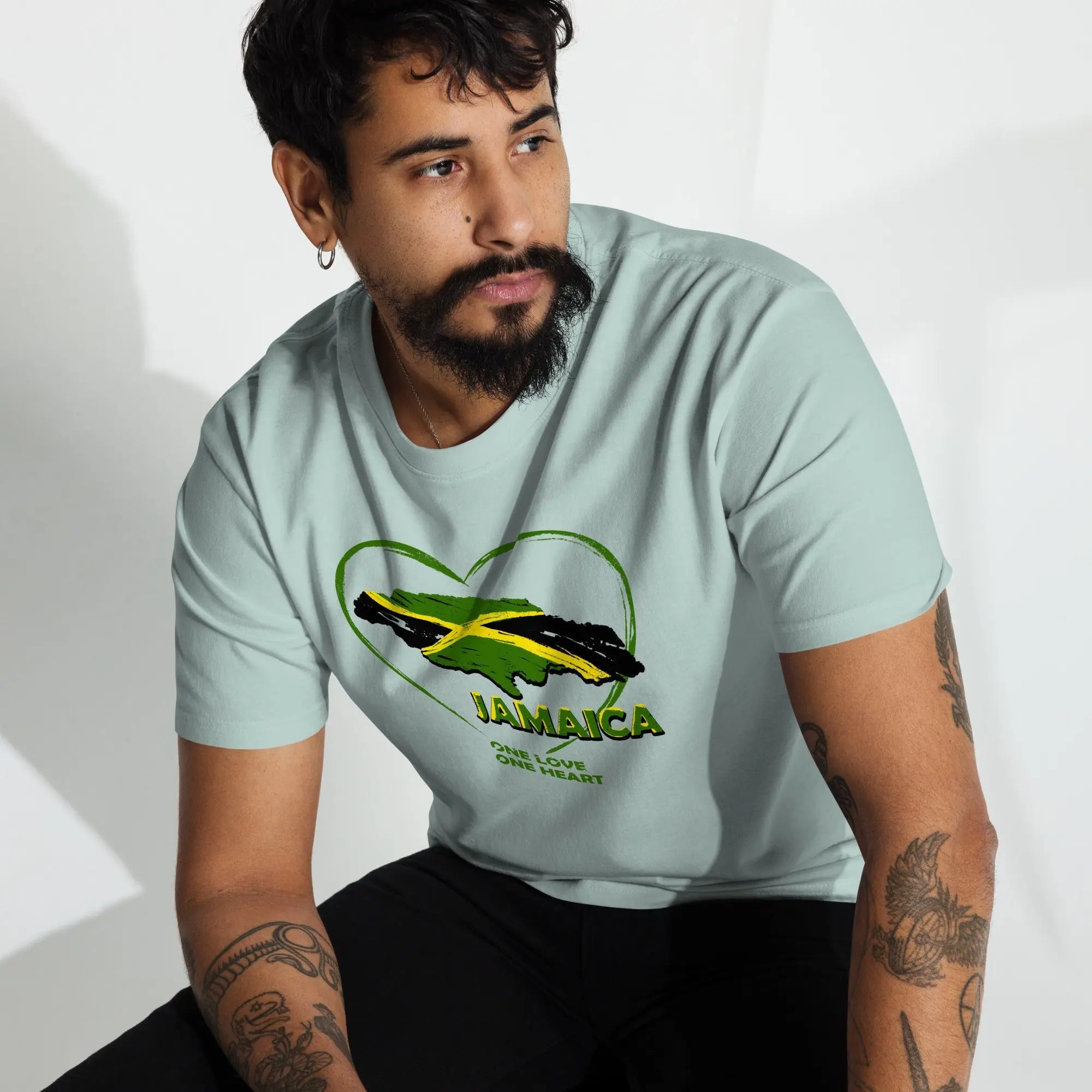 Man wearing a light blue Jamaica One Love One Heart t-shirt with a Jamaican flag heart design and text on front