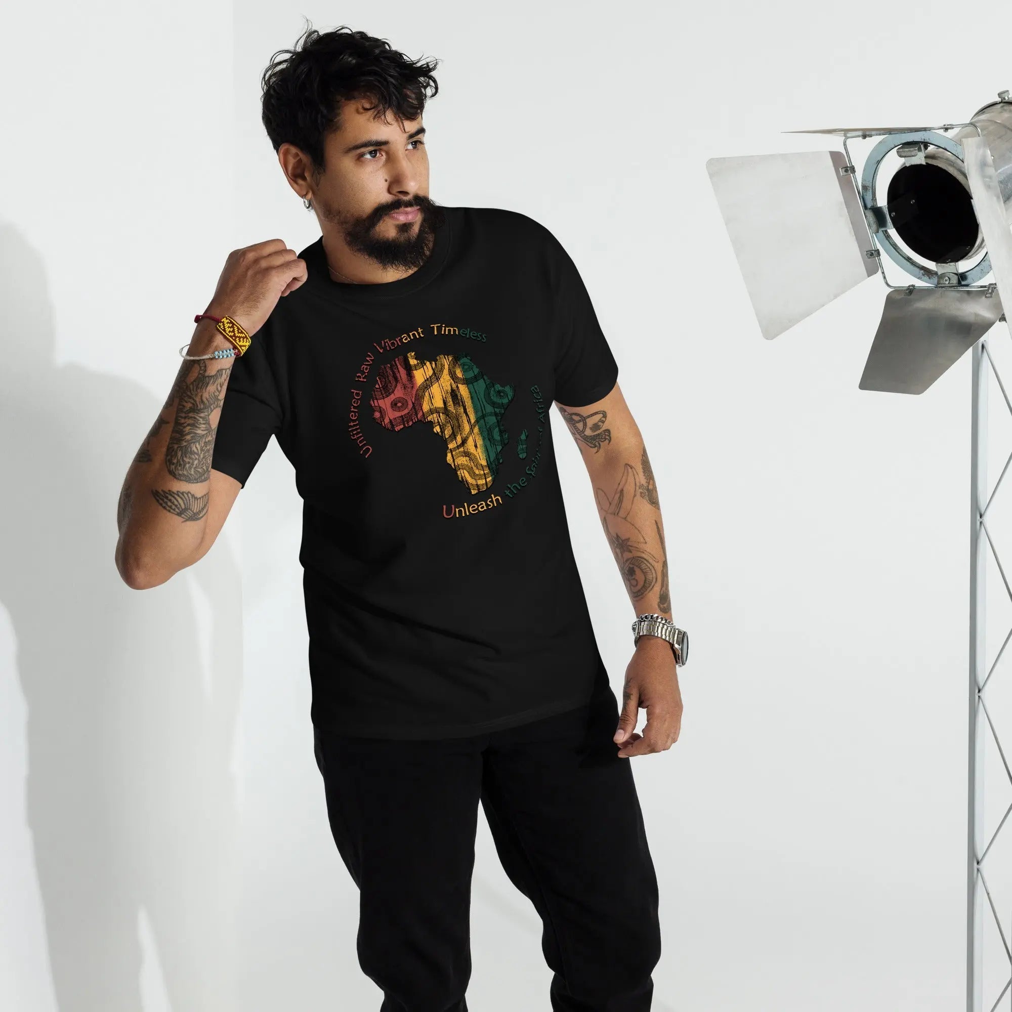 Man wearing black Spirit Of Africa premium heavyweight tee with colorful Africa map graphic and text, styled casually with tattoos and wristwatch.