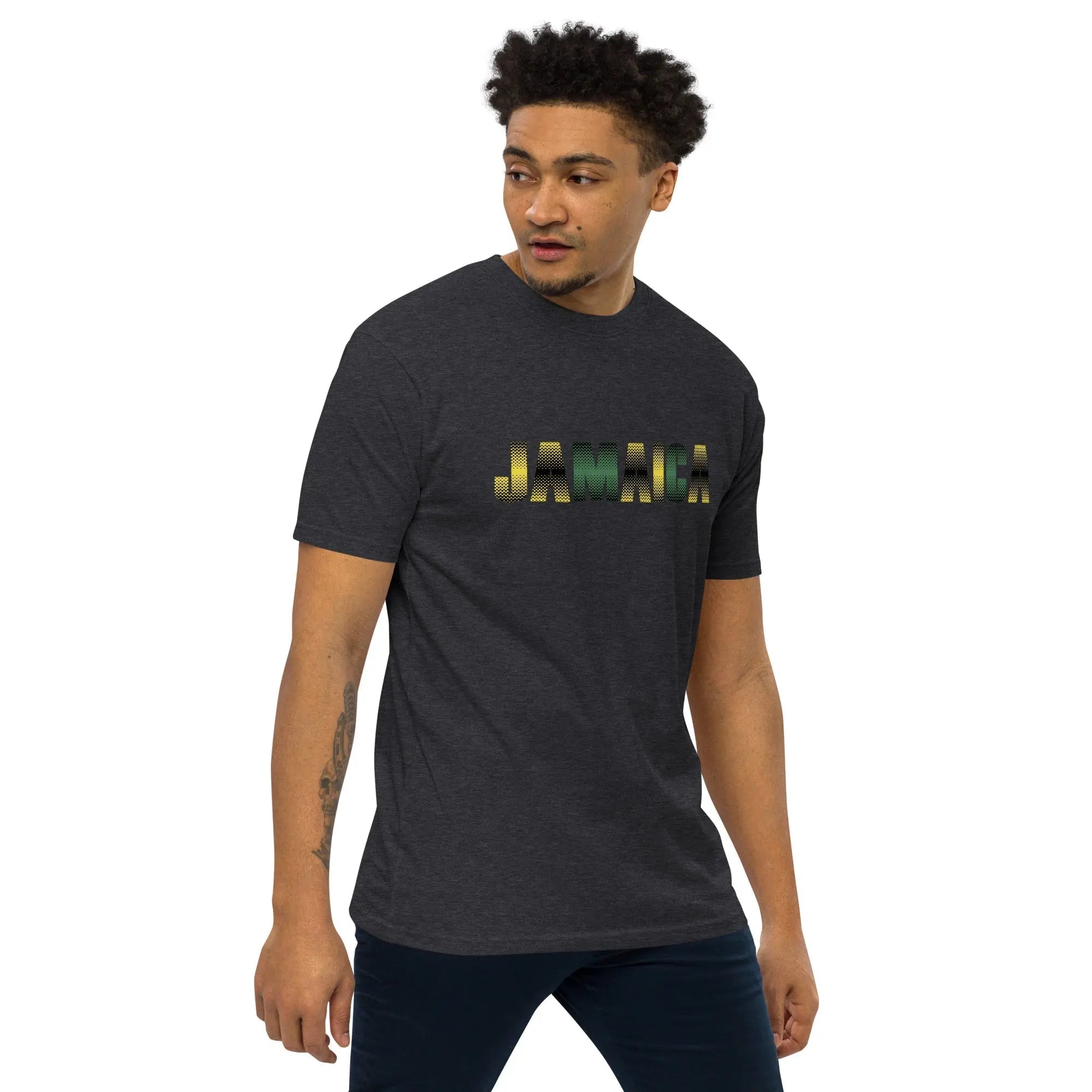 Man wearing Jamaica Out Of Many One People men's premium heavyweight charcoal t-shirt with gold and green lettering