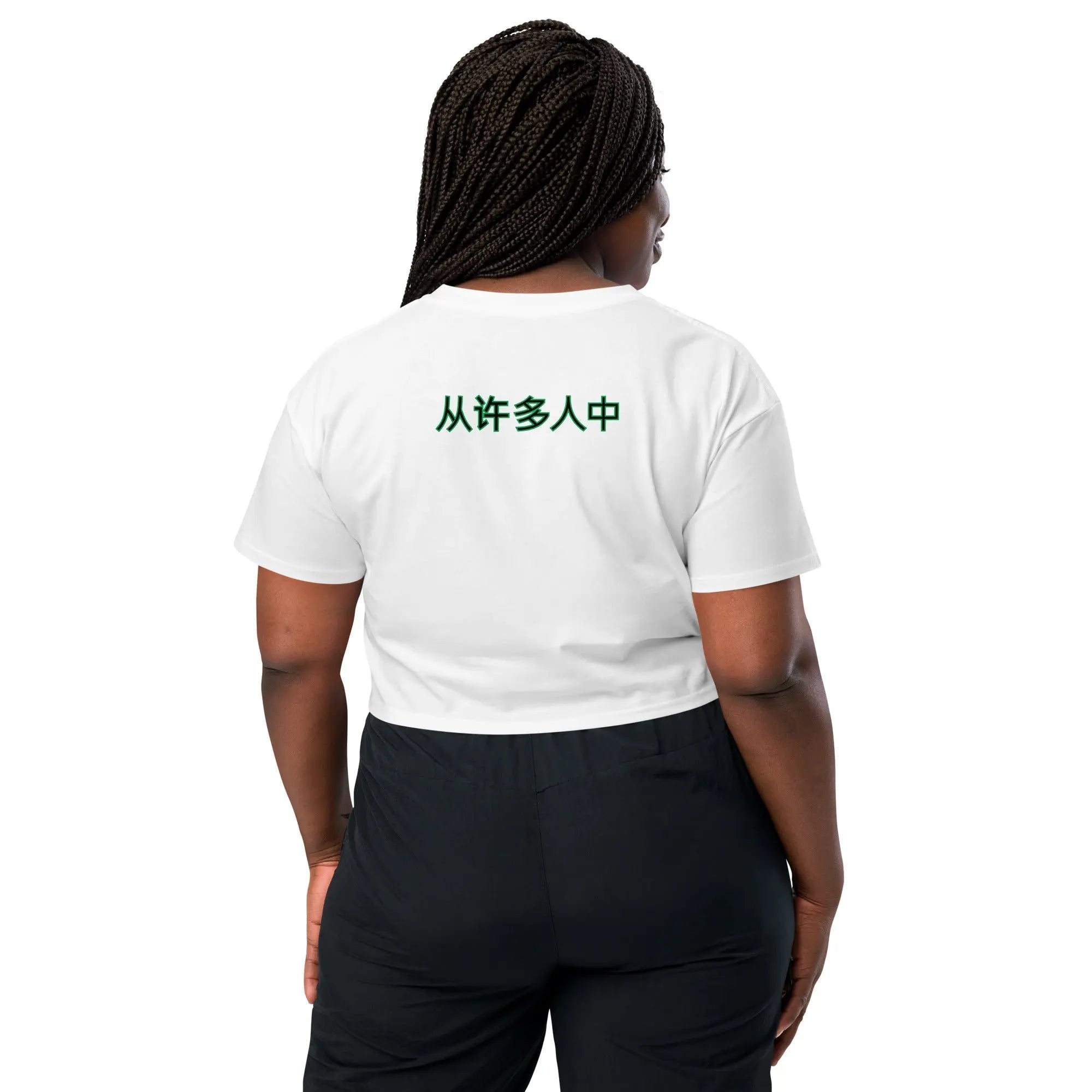 Woman wearing white Out Of Many One women's crop top with green Chinese text on back, black pants, braided hair, standing facing away