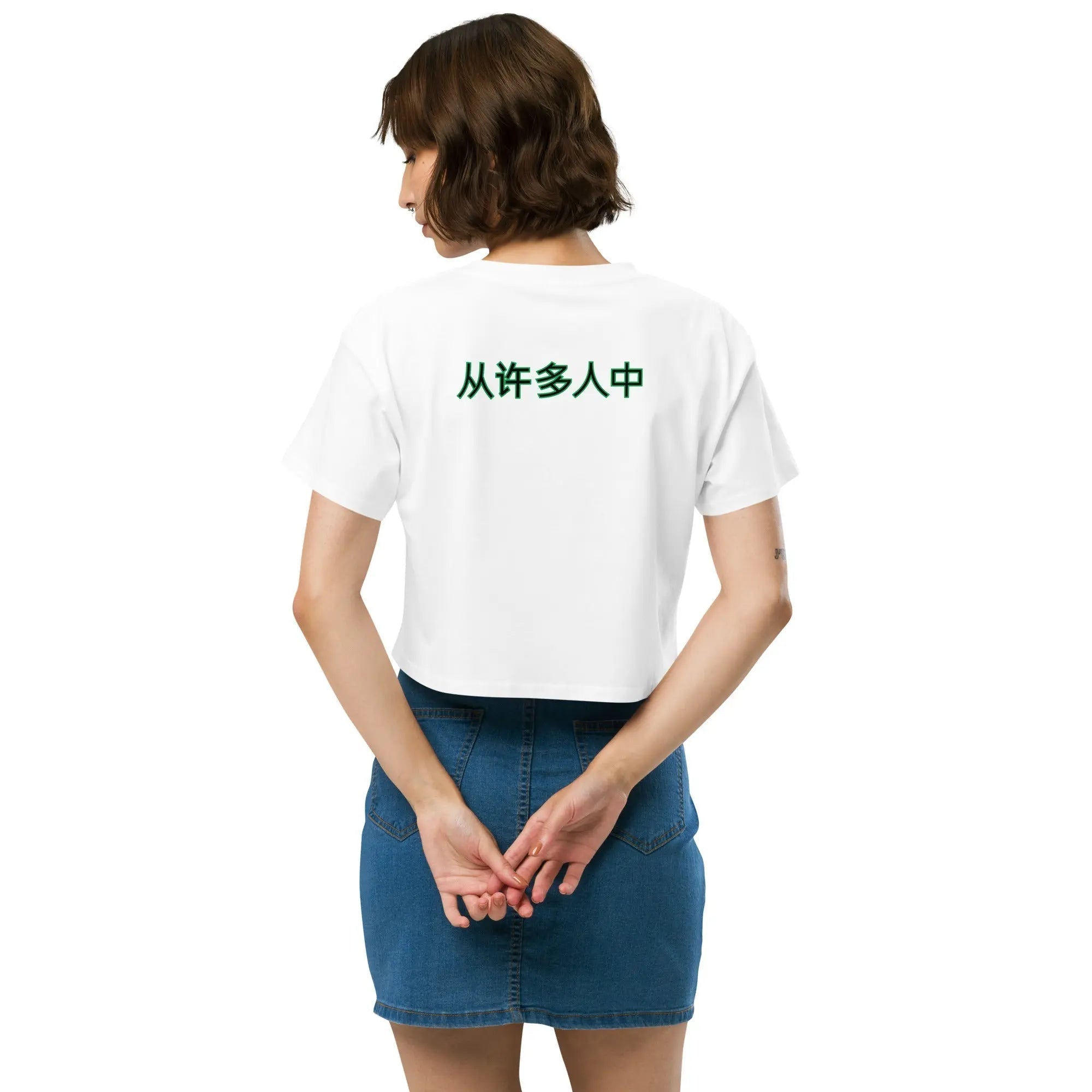 Woman wearing white Out Of Many One People crop top with green Chinese characters on back and denim skirt