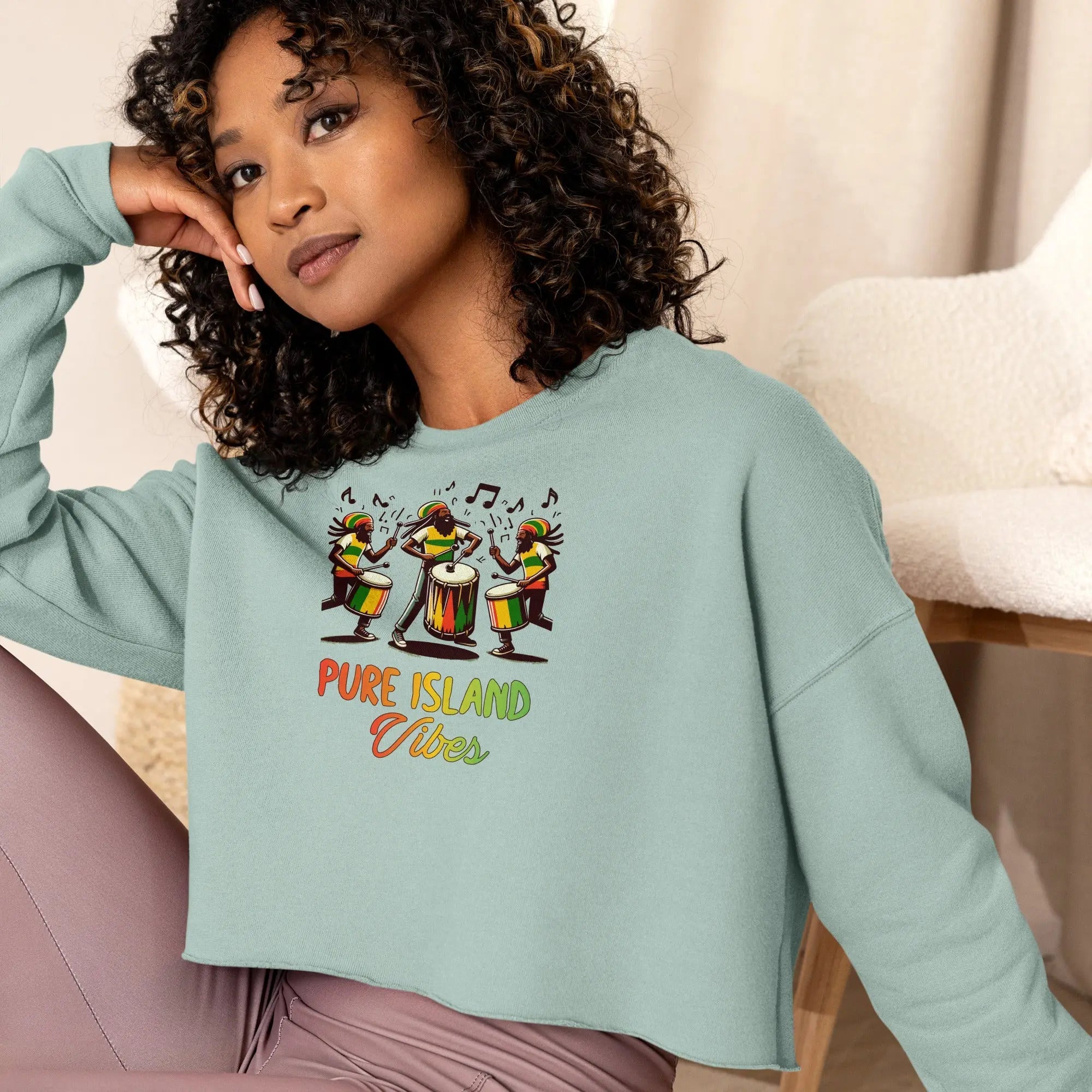 Woman wearing a light blue Pure Island Vibes cropped sweatshirt with vibrant drummers design.