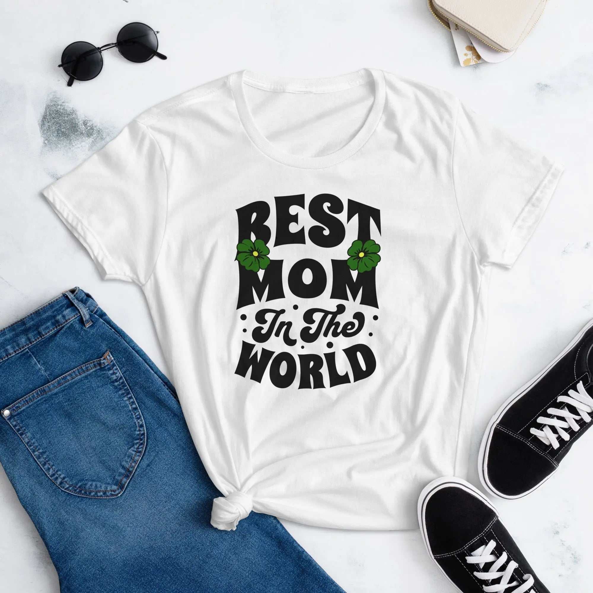 White Best Mom Women's short sleeve t-shirt with floral text design, paired with blue jeans and black sneakers on a white background